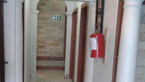A hallway with a clock, a fire alarm, and a staircase.
