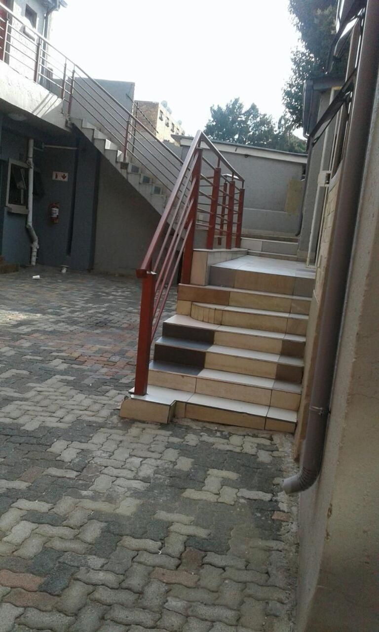 A set of outdoor stairs leading to a building entrance, with a metal handrail and a fire hydrant visible on the left.