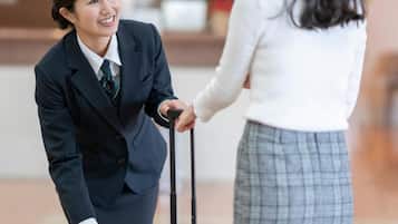 A hotel reception area with a reception desk and a guest with luggage.