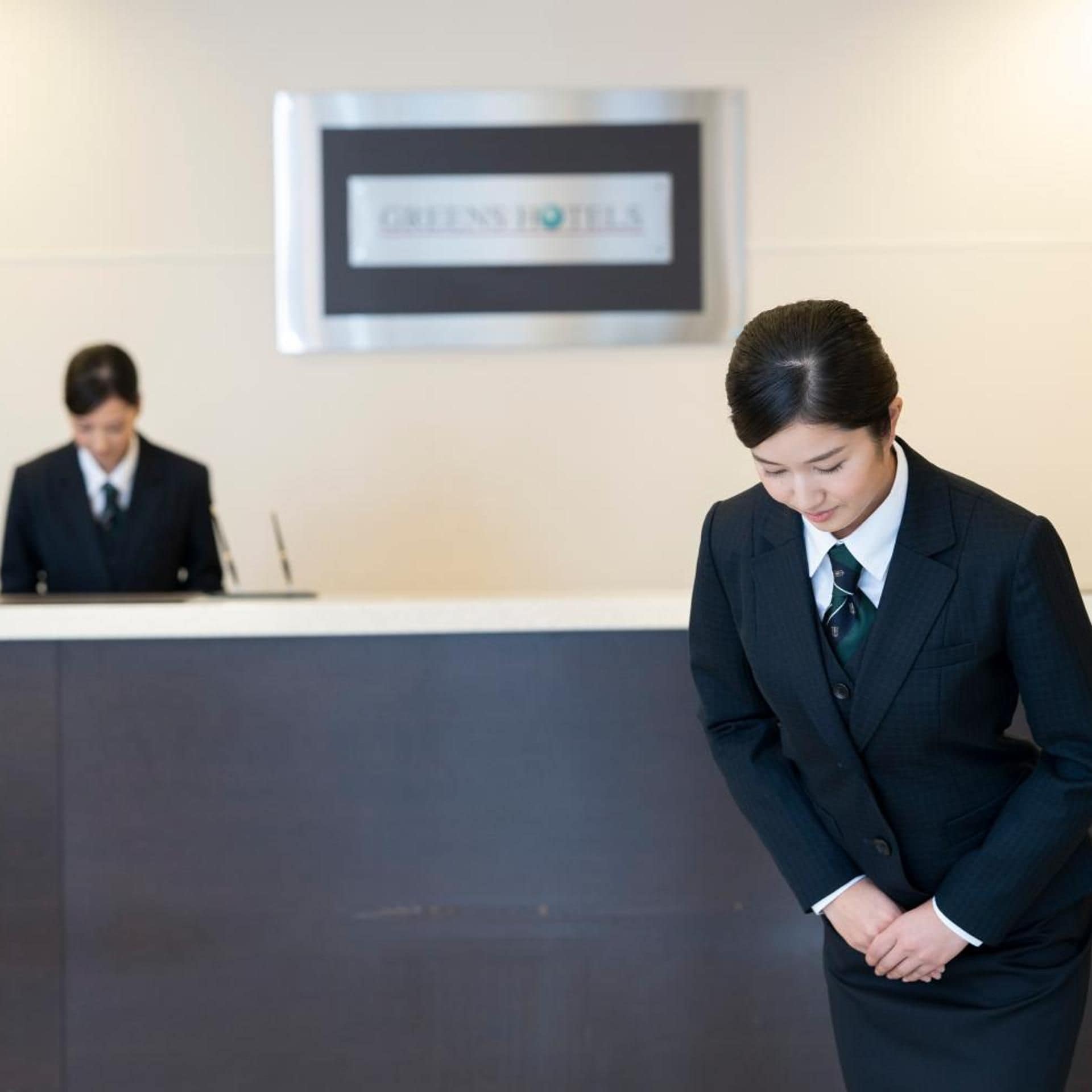 A hotel reception area with a reception desk and a sign that reads 'GREEN HOTEL'.