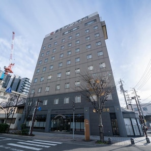 A multi-story hotel building with a modern architectural design, featuring a prominent entrance and a visible signboard.