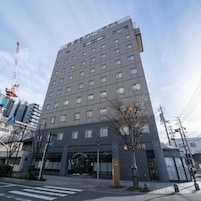 Un edificio de hotel de varios pisos con un diseño arquitectónico moderno, que presenta una entrada destacada y una señalización visible.