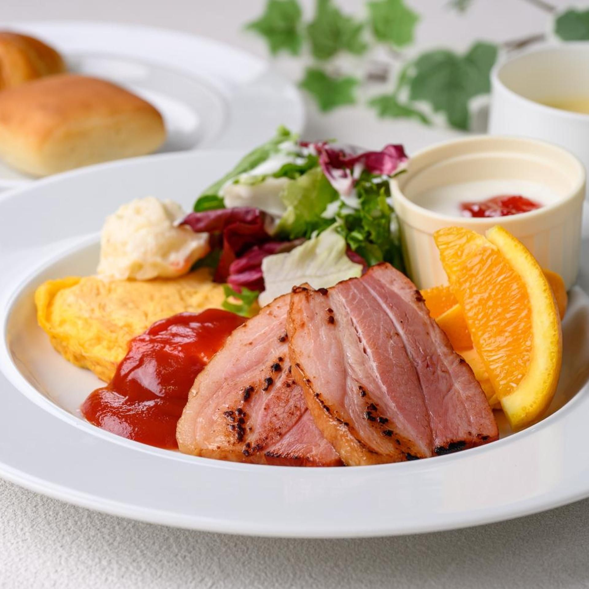 Un piatto con prosciutto a fette, spicchi d'arancia, ketchup e un'insalata come contorno.