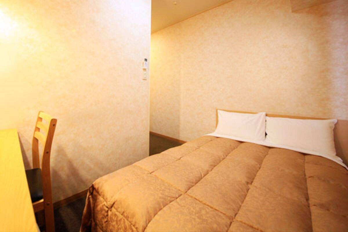 A hotel room with a bed, a chair, and a lamp.