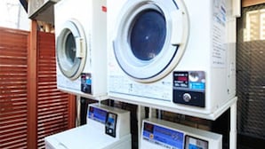A row of stacked washing machines in a commercial setting. - Hachioji Urban Hotel (Hachioji)