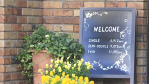 A welcome sign with pricing for single, semi-double, and twin rooms. - Hachioji Urban Hotel (Hachioji)