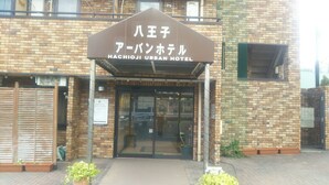 The entrance to Hachijo Urban Hotel with a brick facade and a sign above the entrance. - Hachioji Urban Hotel (Hachioji)