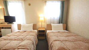 A hotel room with two beds, a desk with a television, and a small refrigerator. - Hachioji Urban Hotel (Hachioji)