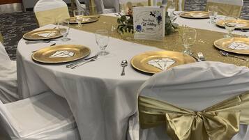 A banquet table set for a wedding with gold and white tableware, chairs with gold sashes, and a sign reading "Your Royal Wedding".