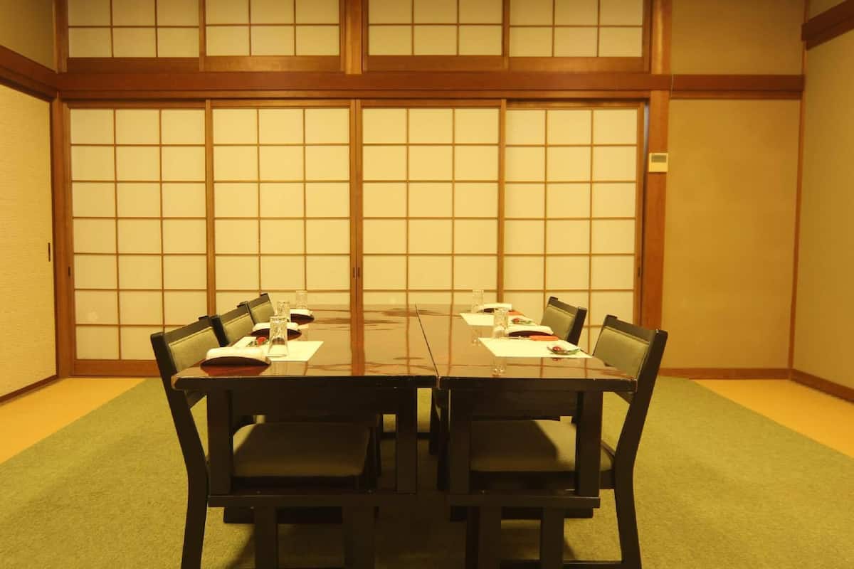 Ein traditioneller japanischer Raum mit Tatami-Boden, einem niedrigen Tisch mit Stühlen und Shoji-Schirmwänden.