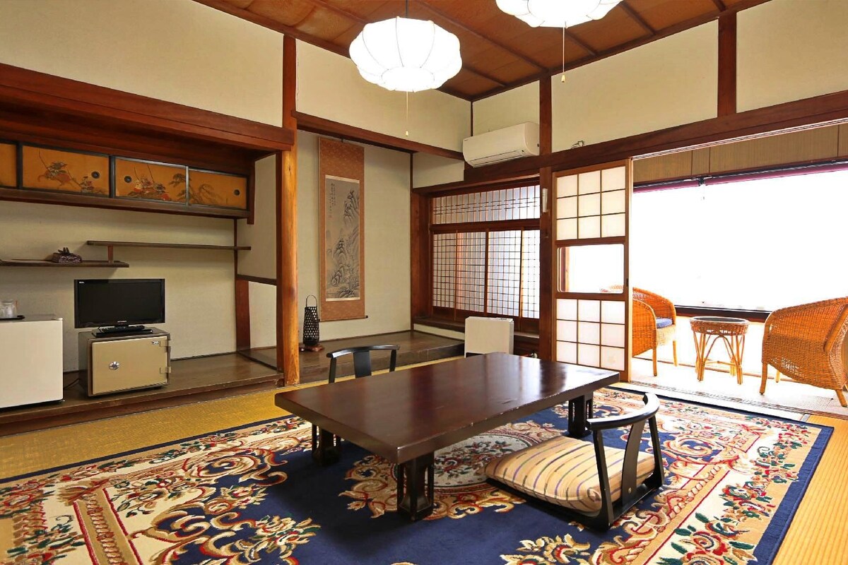 A traditional Japanese room with tatami flooring, a low table, and sliding doors.