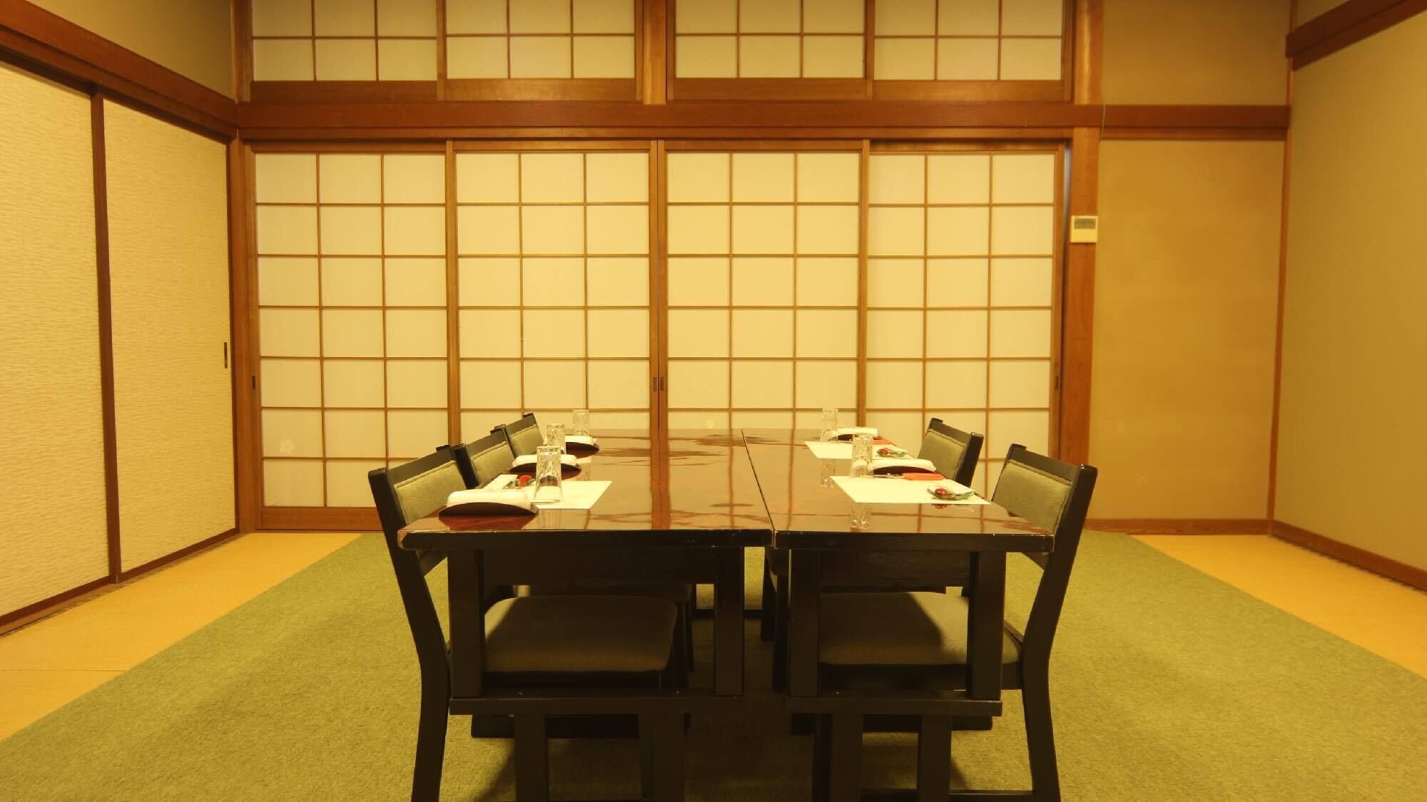 A traditional Japanese room with tatami flooring, a low table with chairs, and shoji screens.