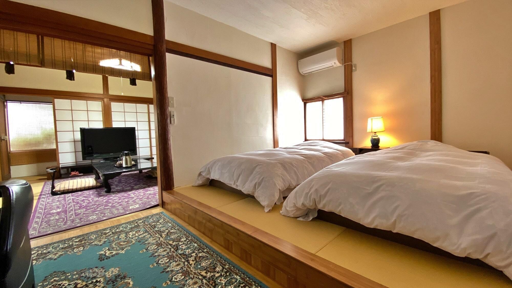 A traditional Japanese-style room with tatami flooring, a television, and a bed with white bedding.