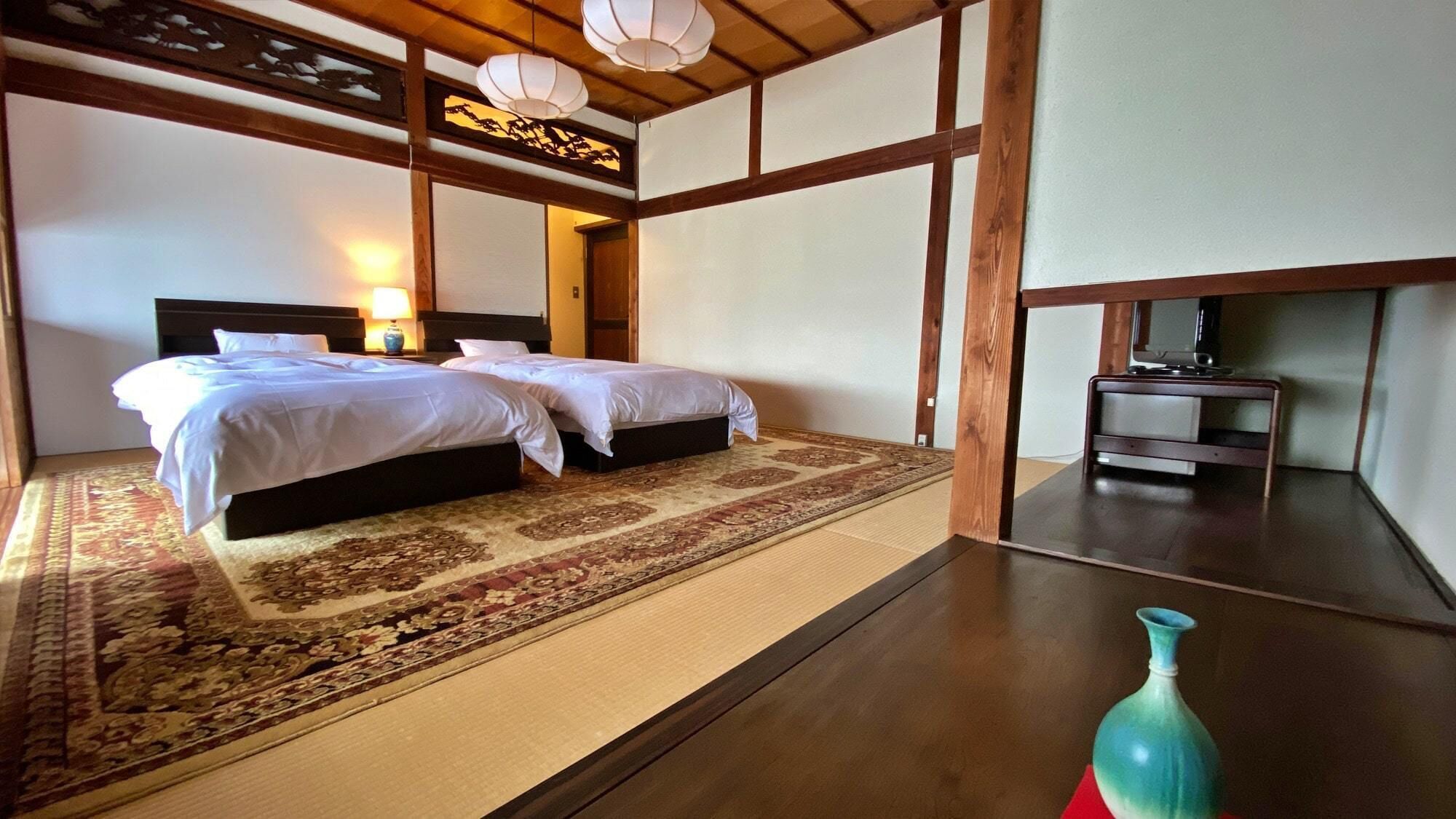 A traditional Japanese-style room with two beds, a tatami mat floor, a wooden table, and a decorative vase.