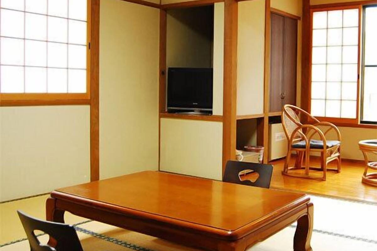 Una habitación tradicional japonesa con suelo de tatami, una mesa baja y un televisor.