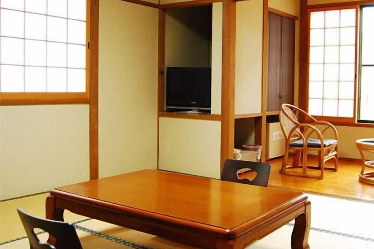 A traditional Japanese-style room with tatami flooring, a low table, and a television.