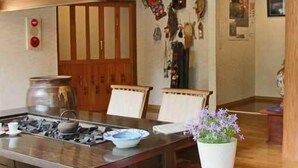 Ein traditioneller japanischer Raum mit Tatami-Böden, einem niedrigen Tisch mit Gasherd und einer Holztür mit Schieberegalsystem.