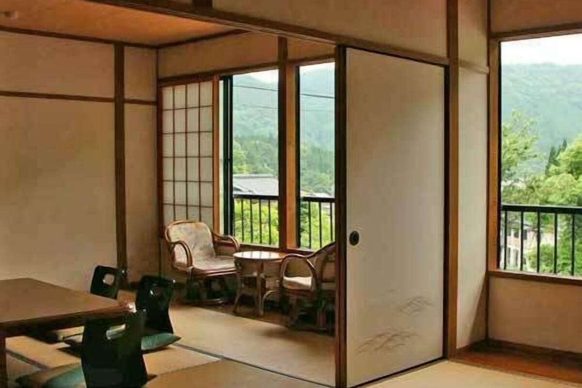 Una habitación tradicional japonesa con esteras de tatami, una puerta corredera, una mesa y sillas.