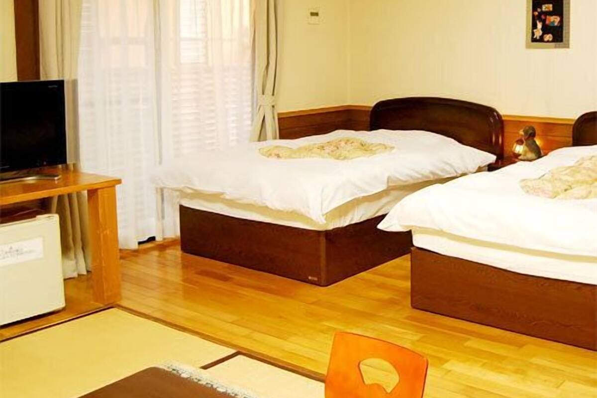 Habitación de hotel con dos camas, televisión y un pequeño escritorio.