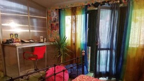 Ein Schlafzimmer mit Bett, Schreibtisch, Stuhl und einem Fenster mit Vorhängen.
