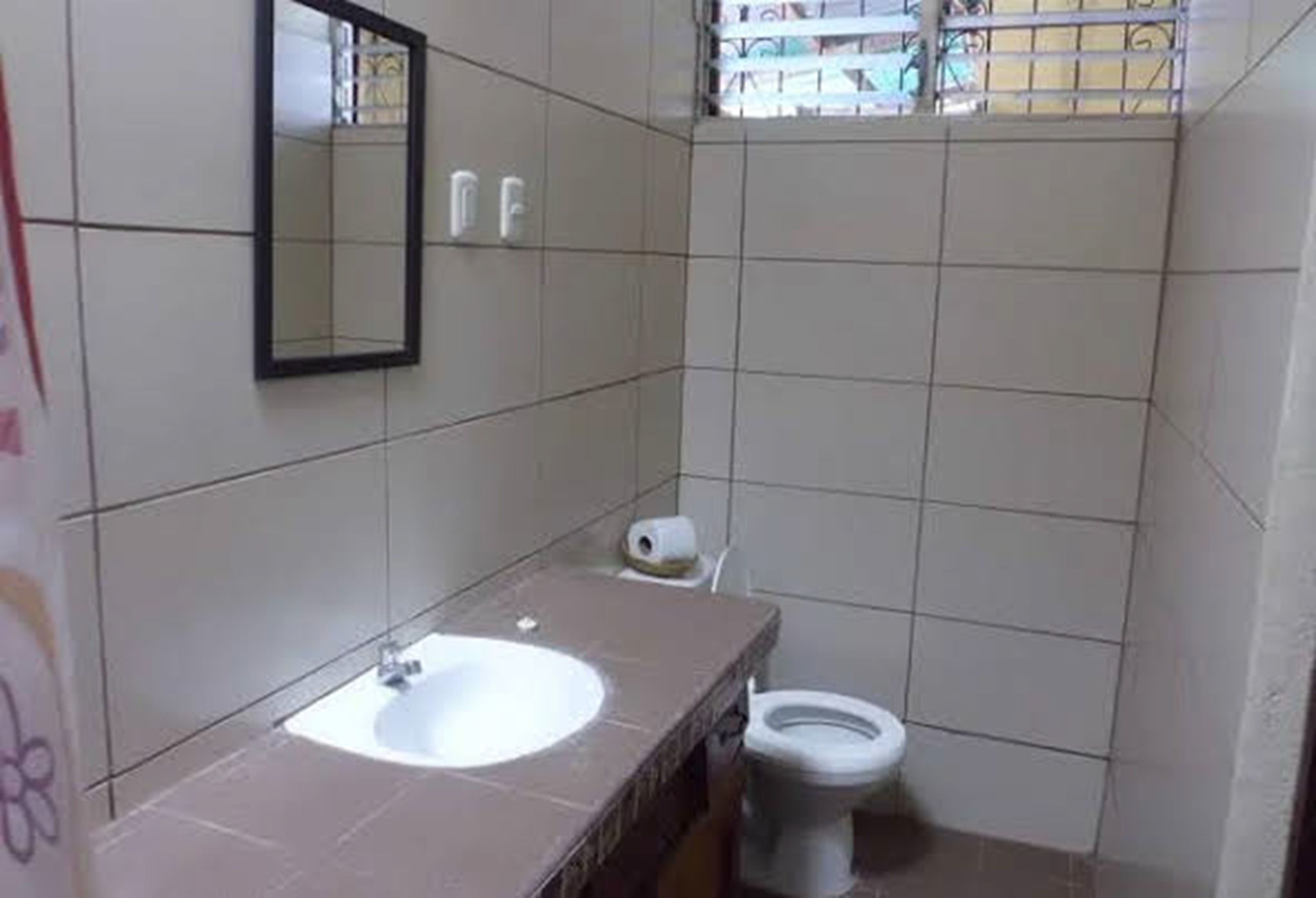 Un baño pequeño con un lavamanos blanco, un espejo y un inodoro.