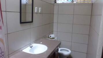 Un baño pequeño con un lavamanos blanco, un espejo y un inodoro.