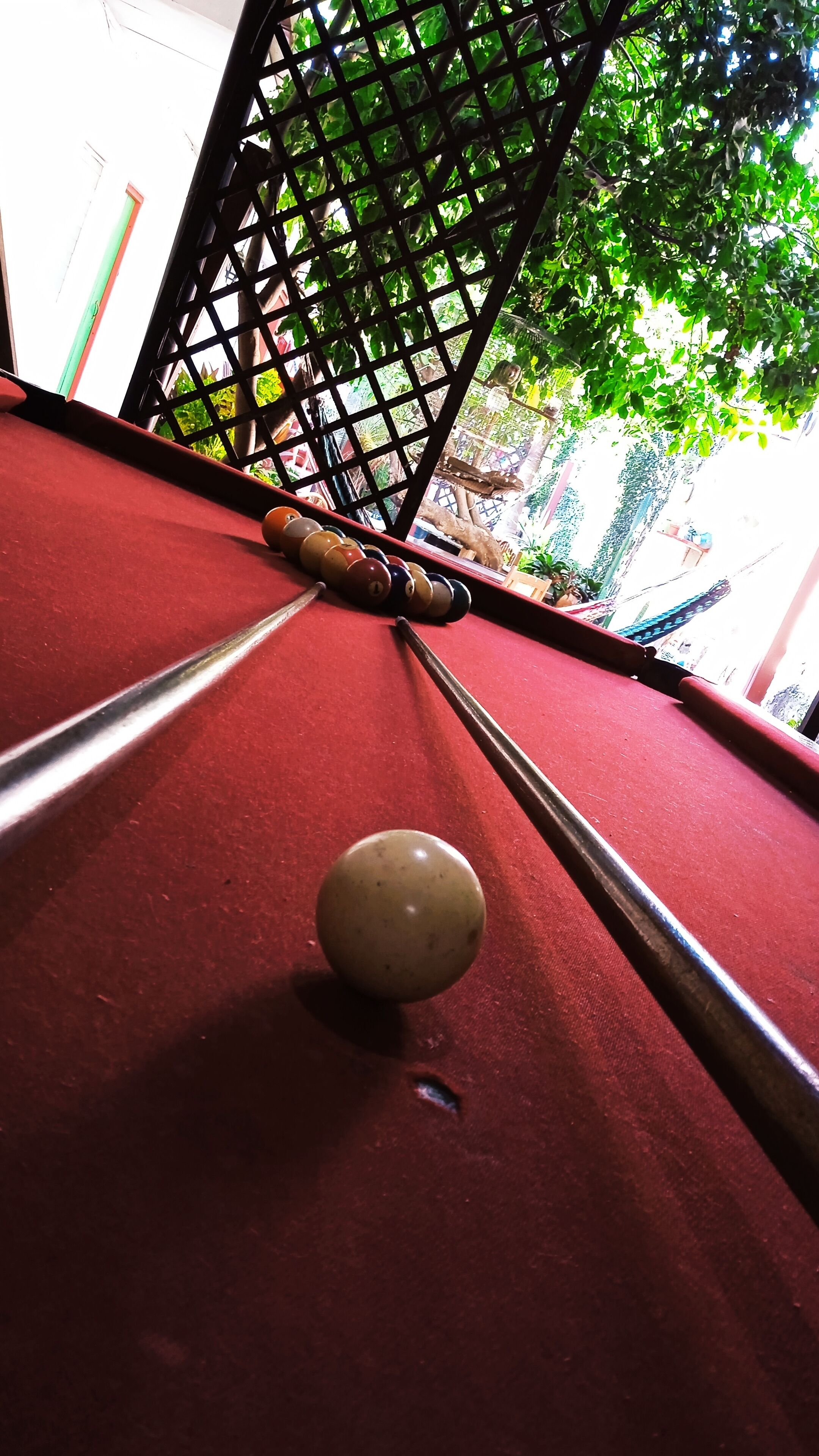 Une vue rapprochée d’une table de billard avec une boule blanche et deux queues, le tout entouré d’une grille noire.