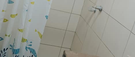 A bathroom with a shower curtain featuring fish patterns, a white sink, and tiled walls.