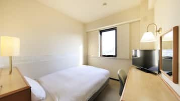 A hotel room with a bed, bedside table, lamp, TV, and a window.