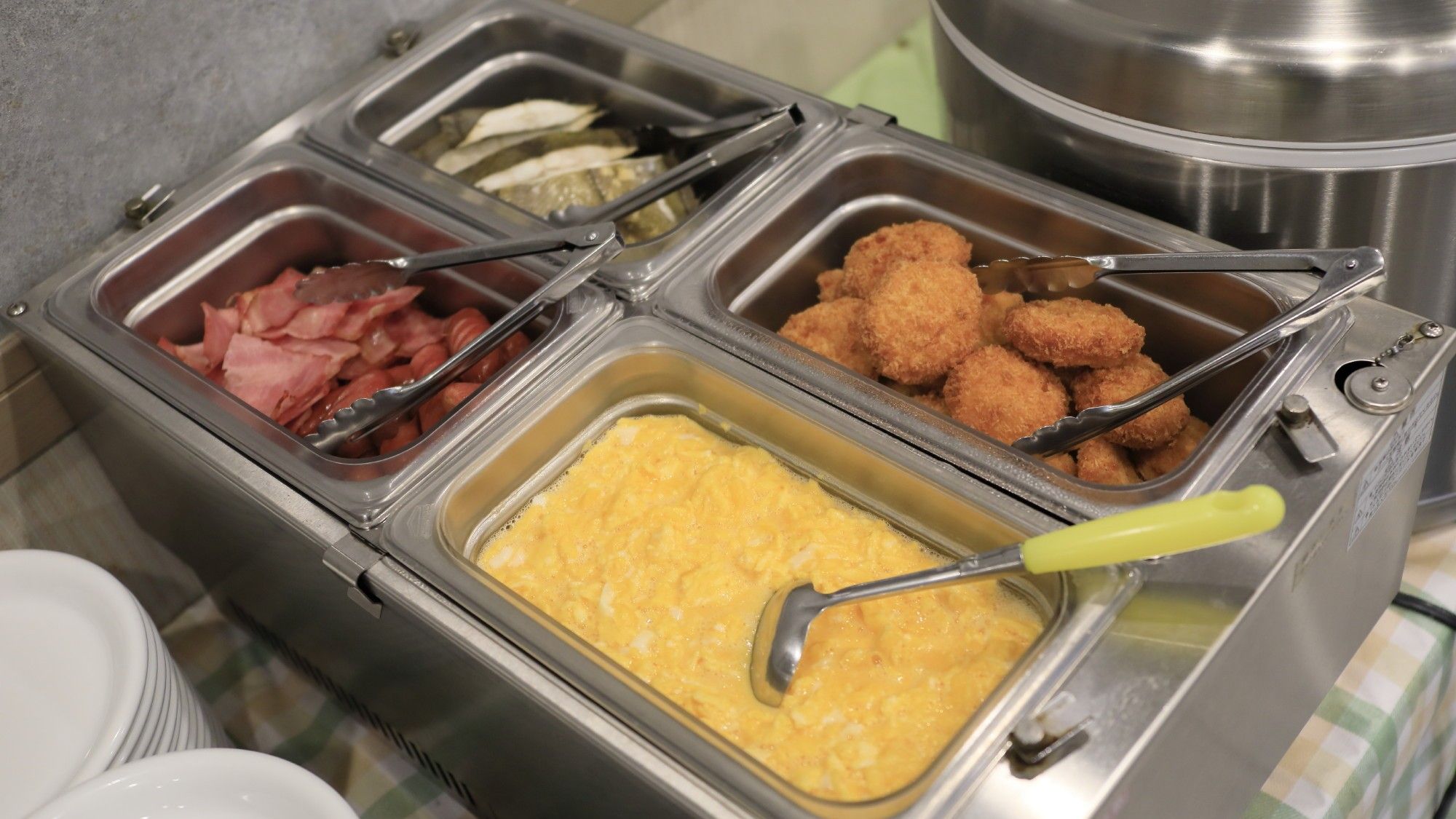 A buffet with various food options including scrambled eggs, bacon, and fried items.