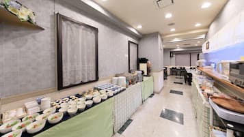 A buffet setup with various food items and a long table covered with a green tablecloth.