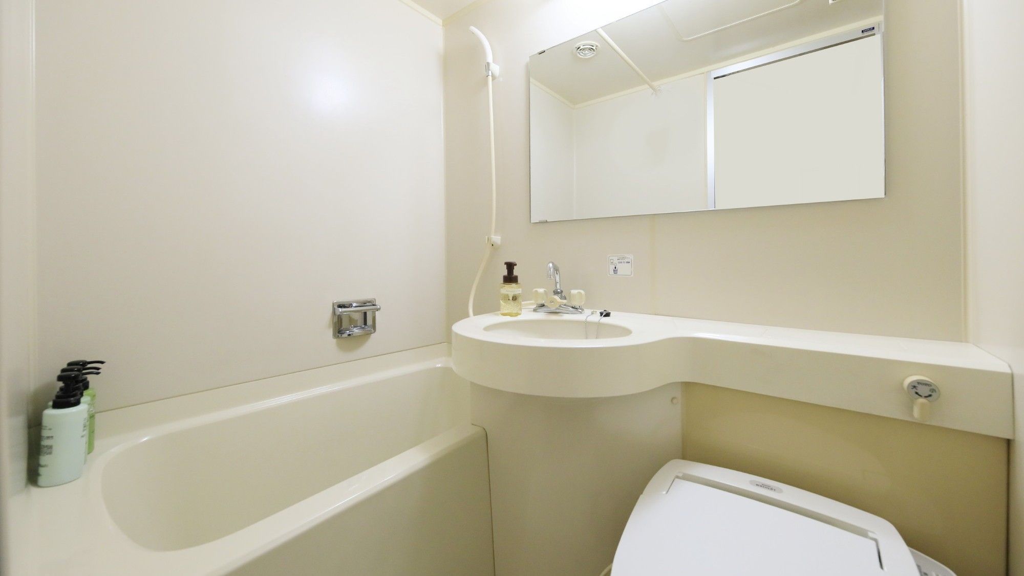A bathroom with a bathtub, a sink, a mirror, and a toilet.