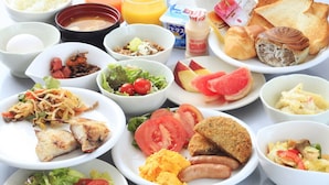 En frukostbuffé med olika rätter, inklusive ägg, rostat bröd, korv och färsk frukt.