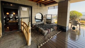 Un espace intérieur-extérieur doté d’un plafond en bois, de murs en pierre, d’un coin salon avec vue et d’un petit sanctuaire.