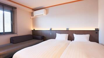 Una habitación de hotel con una cama grande, un sofá y una ventana con persianas.