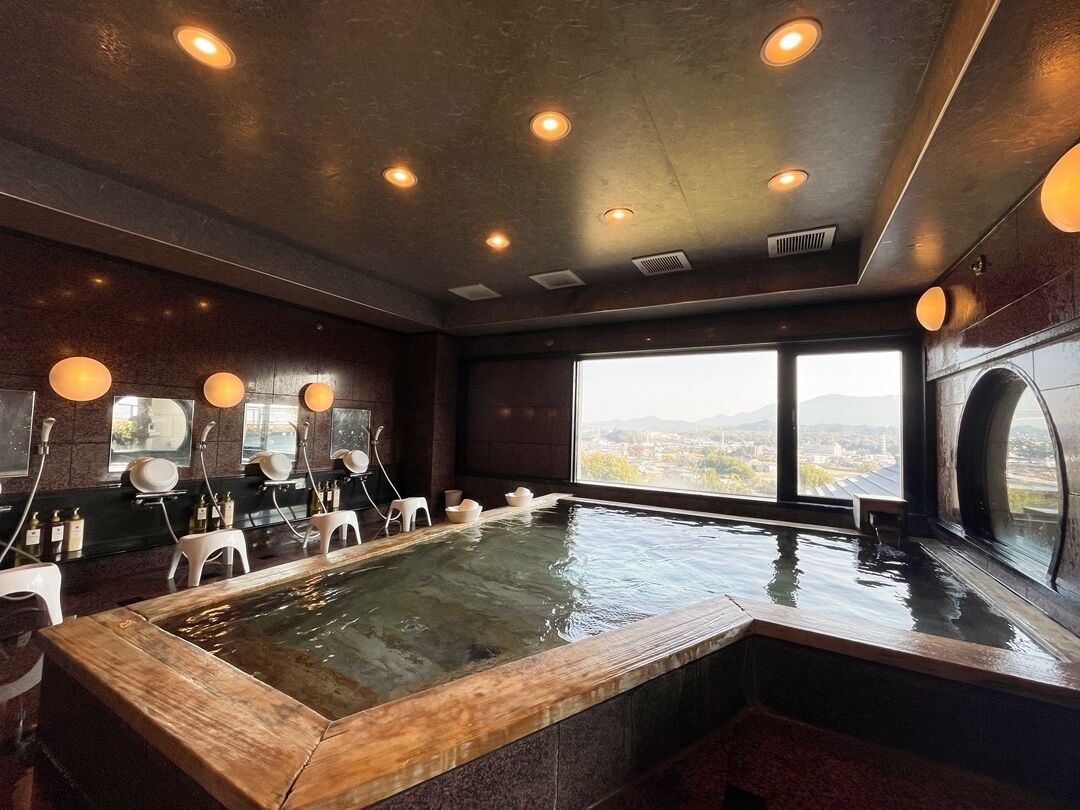 A spa room with a large hot tub, seating area, and a view of the city.