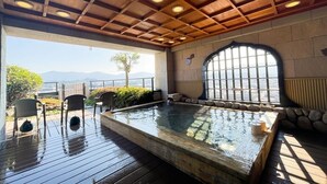 Un espace avec un bain à remous, une terrasse en bois, des chaises et une vue sur les montagnes.