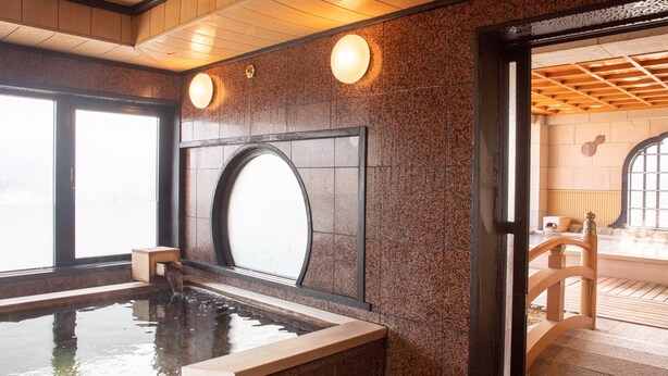Un espace spa doté d’un jacuzzi, d’un plafond en bois et de murs en pierre.