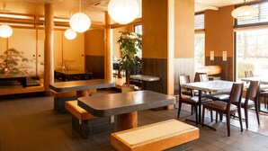 L’intérieur d’un restaurant est agrémenté de tables et de bancs en bois, de lanternes en papier suspendues et d’une grande fenêtre qui laisse entrer la lumière naturelle.