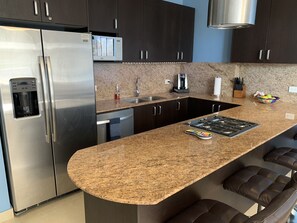 Eine moderne Küche mit einem Edelstahl-Kühlschrank, einer eingebauten Mikrowelle, einer Kaffeemaschine und einem Gasherd.