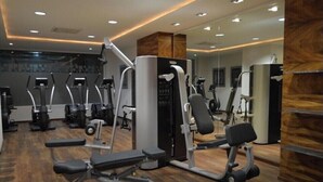 Een moderne sportschool met diverse fitnessapparaten, houten vloeren en een grote spiegel.