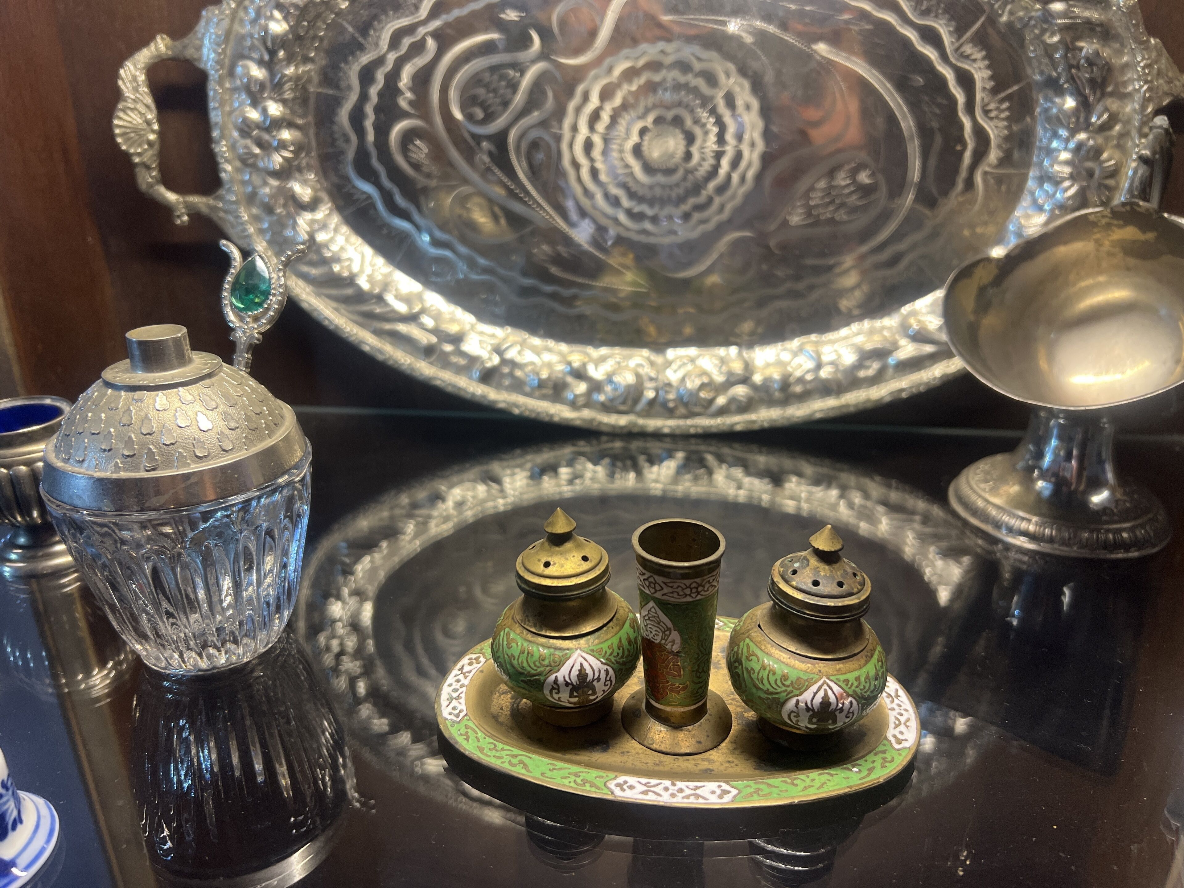 A display of antique silverware and glassware with intricate designs.