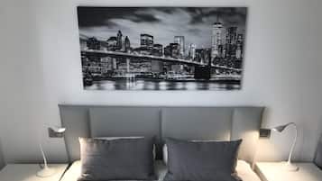 Une chambre avec vue sur la ville, deux tables de chevet avec des lampes et un lit recouvert d’une couvre-lit à motifs.