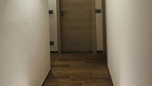 Ein schmaler Korridor mit Holzboden und einer Tür am Ende.