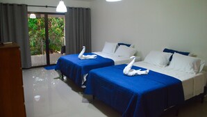 A hotel room with two beds, a balcony with curtains, and a view of greenery outside. - Casa Brillasol Samara (Sámara)