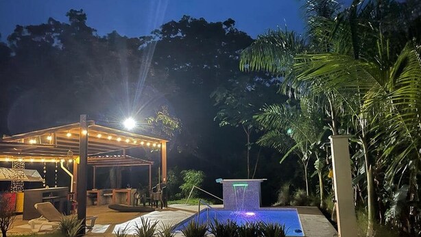 An outdoor patio area with a covered seating area, a small pool with a waterfall feature, and surrounding greenery. - Casa Brillasol Samara (Sámara)
