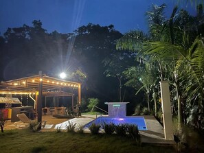 An outdoor patio area with a covered seating area, a small pool with a waterfall feature, and surrounding greenery. - Casa Brillasol Samara (Sámara)