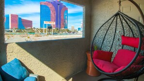 A room with a hanging chair, a view of a cityscape, and a large window.