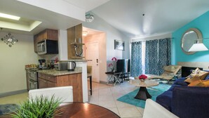 A modern living room with a sofa, coffee table, and a dining area with a table and chairs.