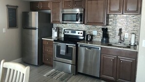 A modern kitchen with stainless steel appliances, wooden cabinets, and a tiled backsplash. - Beautiful Direct Ocean Front View Condo (New Smyrna Beach)